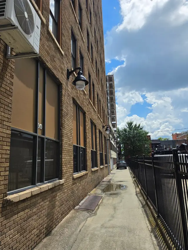 Black gooseneck lanterns installed in a line along a brick alley elevation