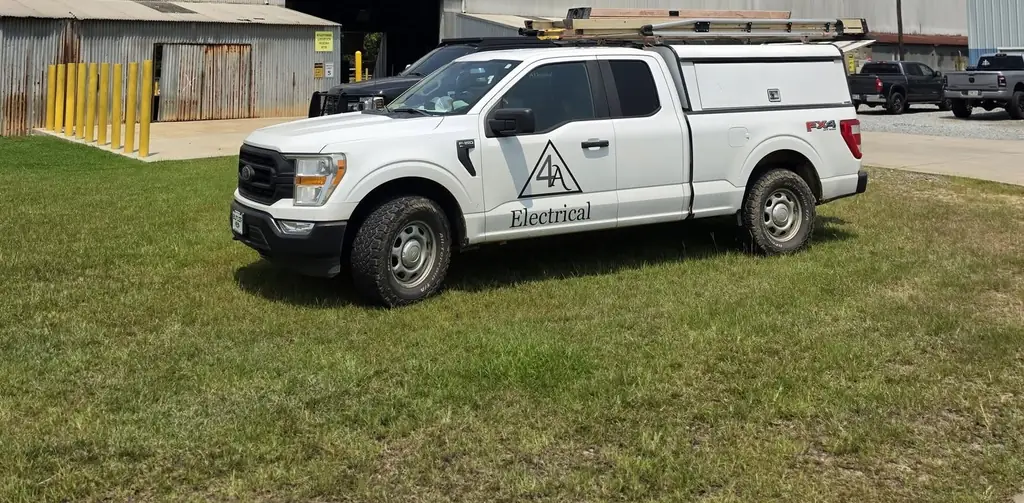 White Ford F-150 with the 4A Electrical triangle livery parked on grass